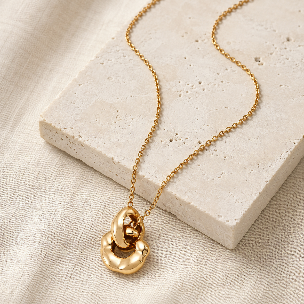 Vintage Gold Interlocking pendant necklace on a stone display