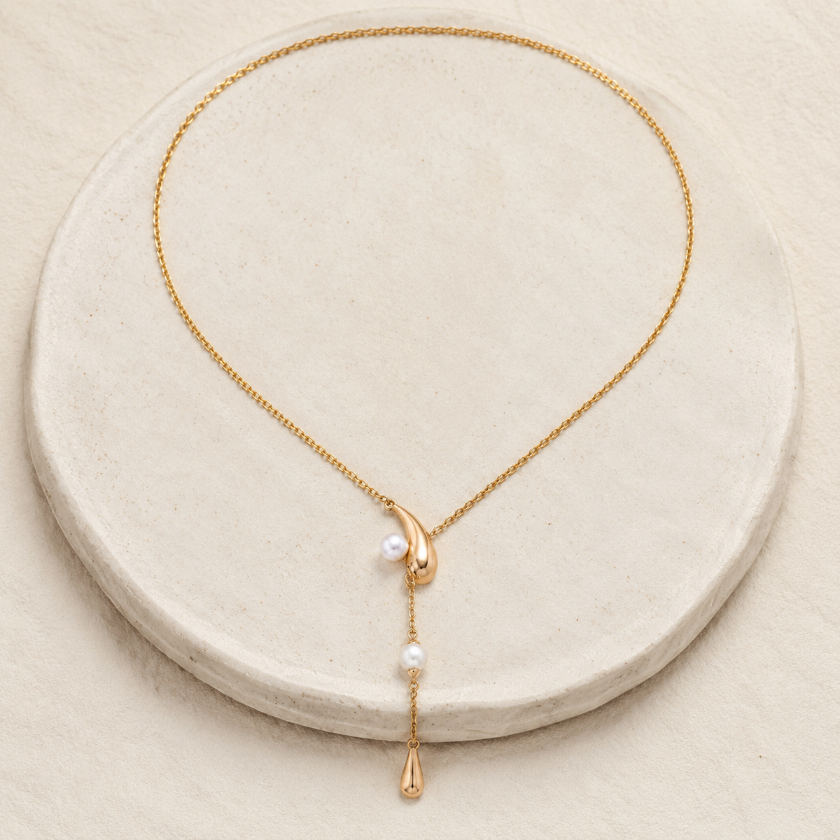 Full view of the Vintage Gold natural pearl meteor wish lariat necklace on a stone display