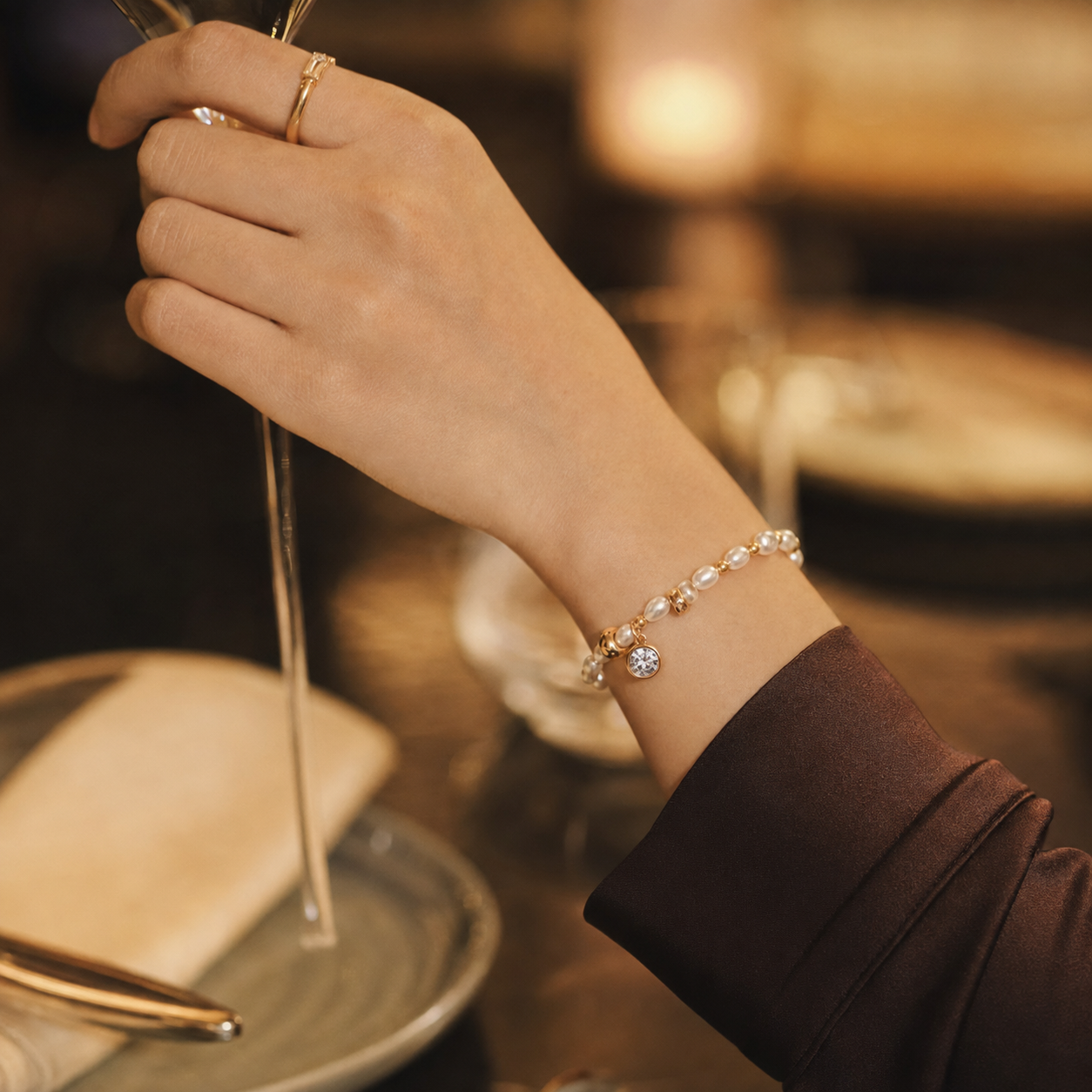 Model wearing the Vintage Gold pearl and cubic zirconia charm bracelet for evening styling