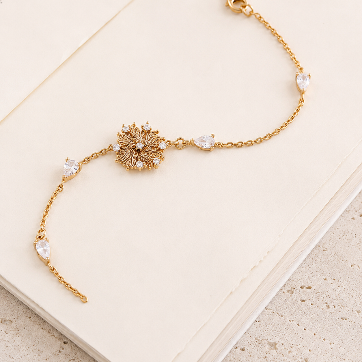 Six-Petal Lily Bracelet in Vintage Gold laid across an open book