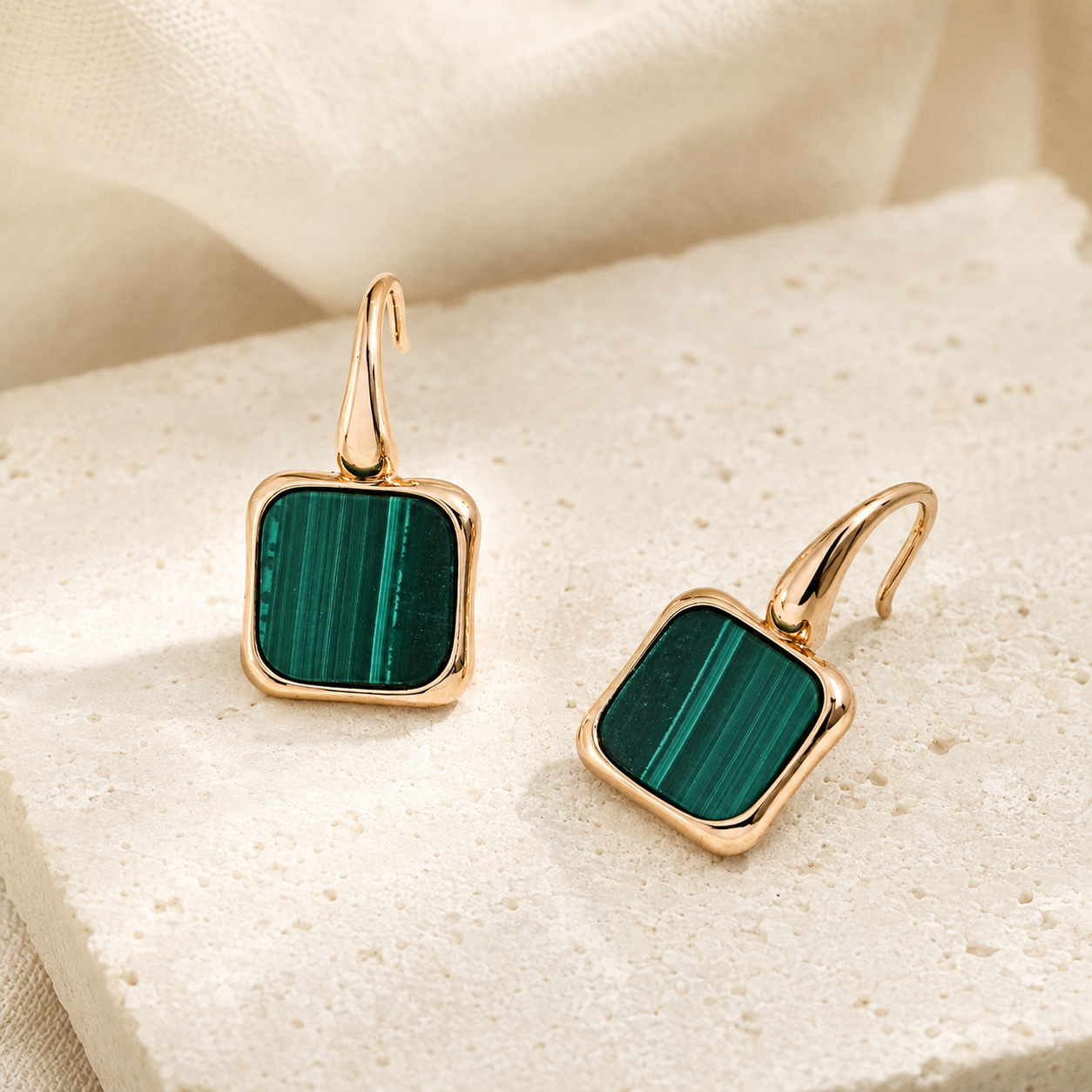 Vintage Gold malachite drop earrings on a stone display