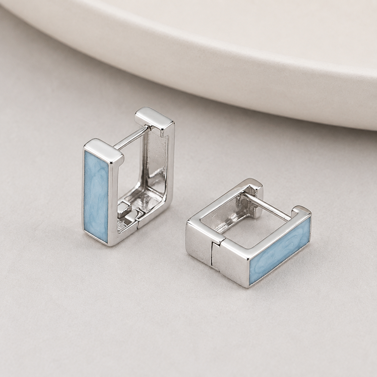 Pair of Silver French enamel drop stud earrings on a stone display