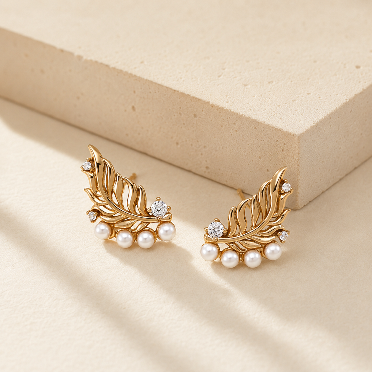Pair of Vintage Gold feather pearl stud earrings in warm light