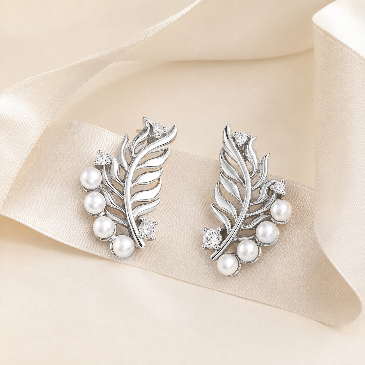 Silver feather pearl stud earrings with natural pearls on an ivory ribbon