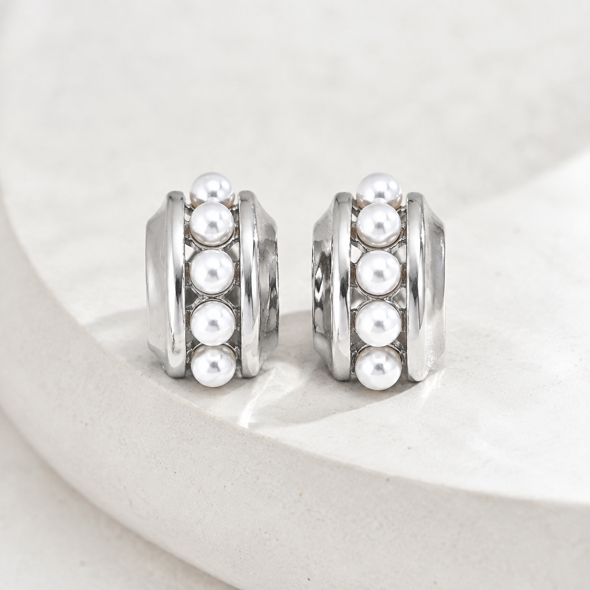 Pair of Silver layered shell pearl stud earrings on a stone display