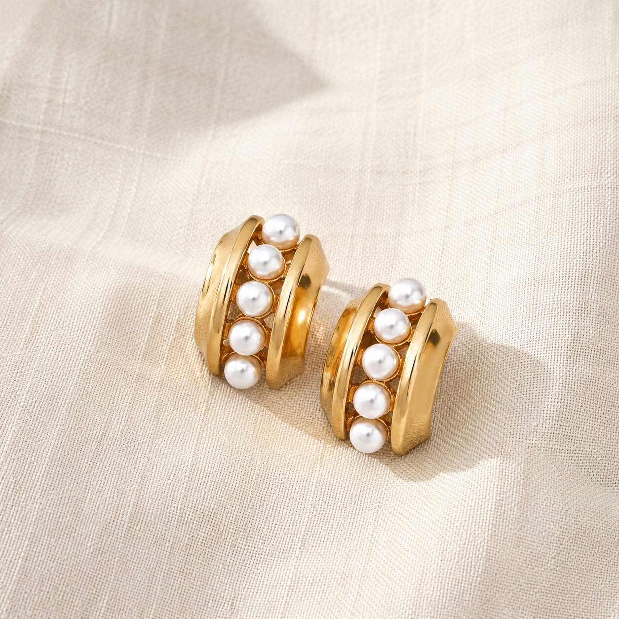 Pair of Vintage Gold layered shell pearl stud earrings on textured fabric