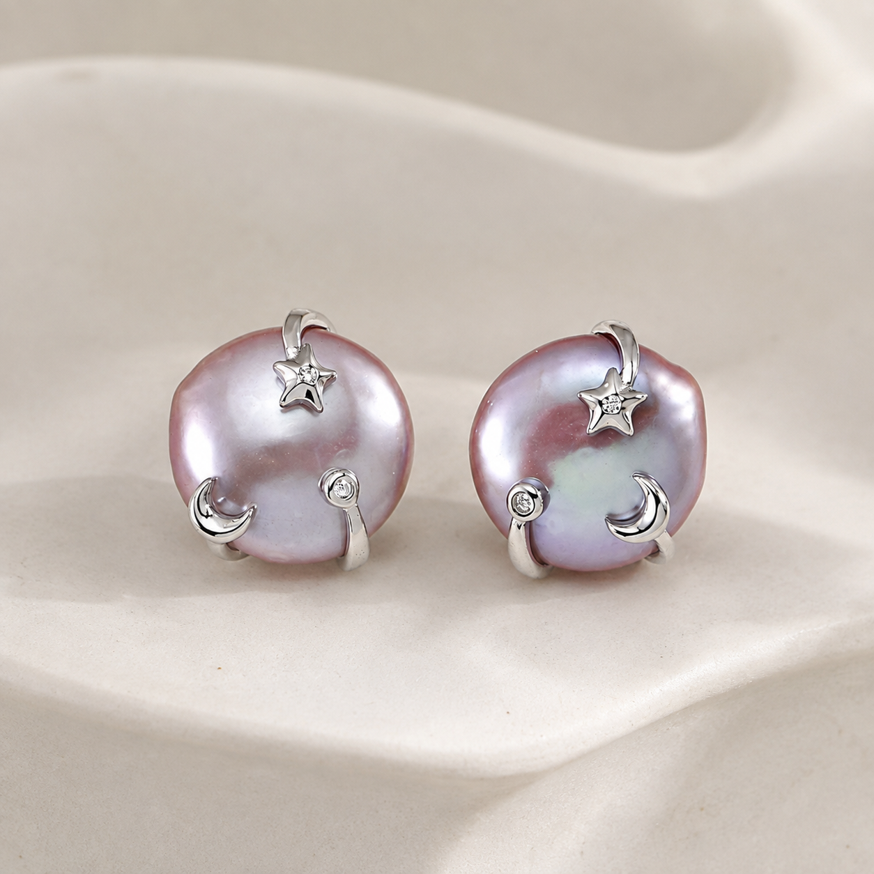 Pair of Silver Wish Pearl Earrings on an ivory display