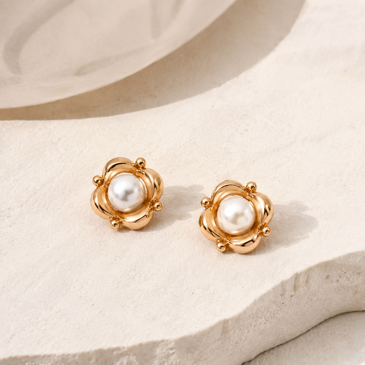 Vintage Gold Orbit Pearl Stud Earrings shown as a pair on an ivory stone display
