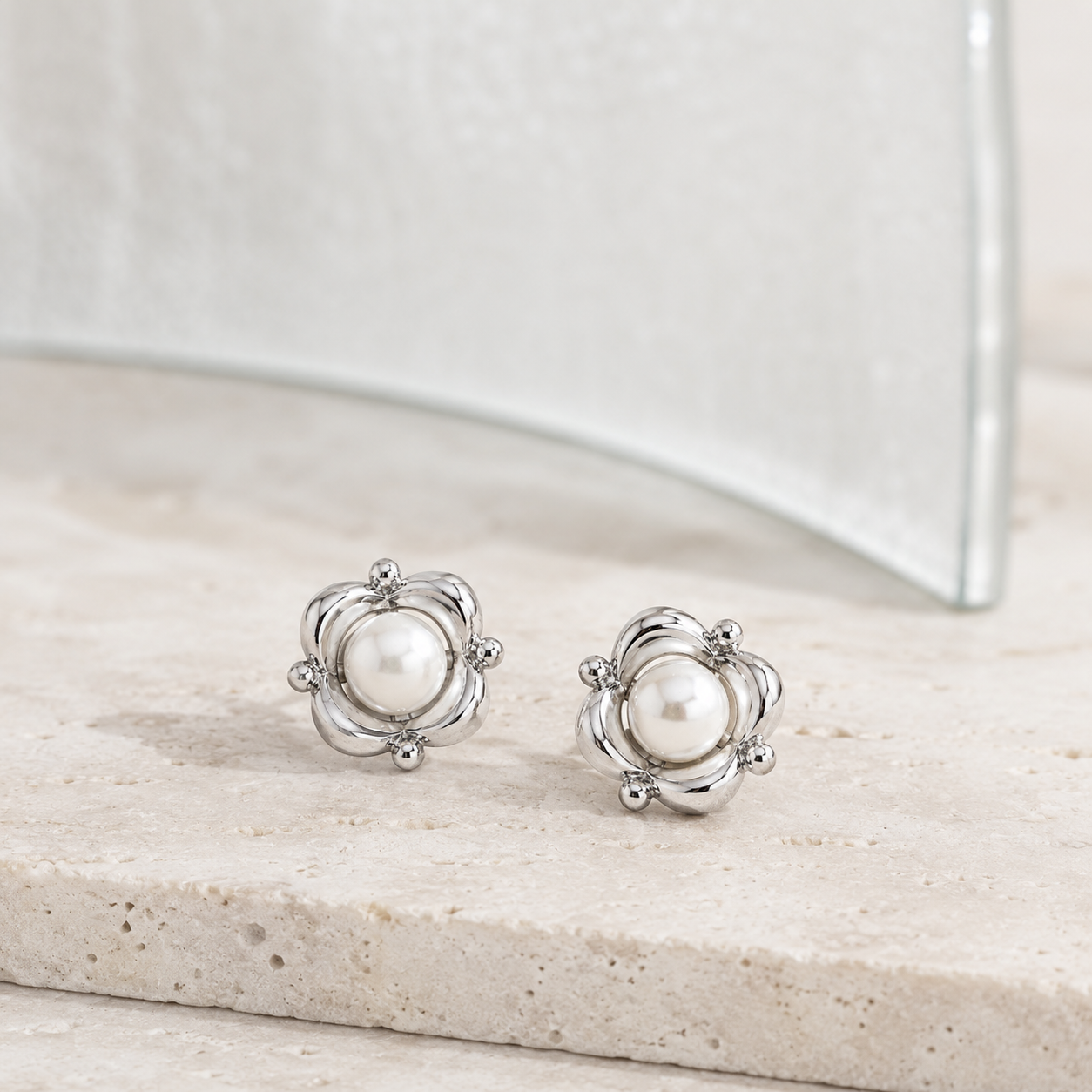 Silver Orbit Pearl Stud Earrings shown as a pair on a pale stone display