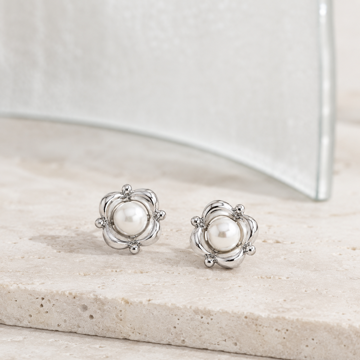 Silver Orbit Pearl Stud Earrings shown as a pair on a pale stone display