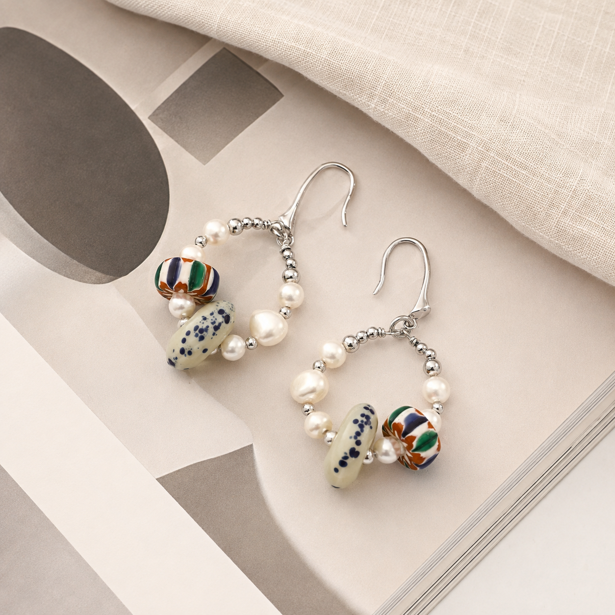 Silver Himalayan Glass Pearl Hoop Earrings styled on an open book