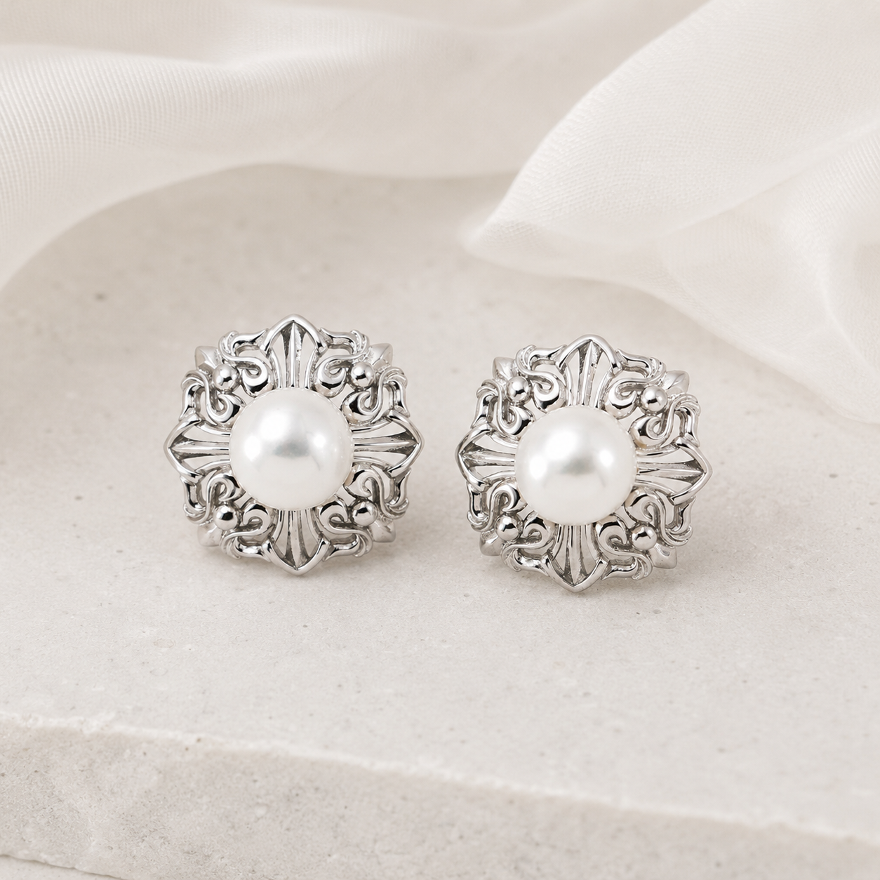 Silver Ornate Pearl Stud Earrings on a light ivory display