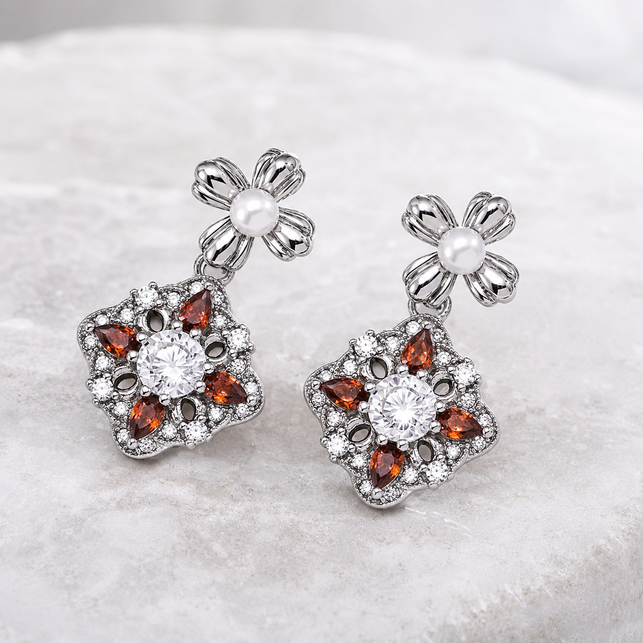 Silver auspicious bloom pearl drop earrings on a marble display