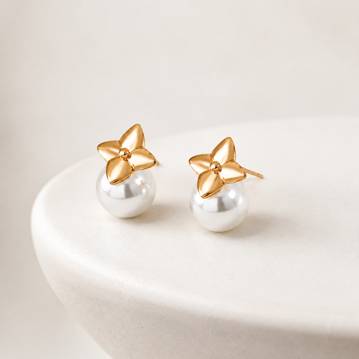 Vintage Gold four-leaf shell pearl stud earrings on an ivory display
