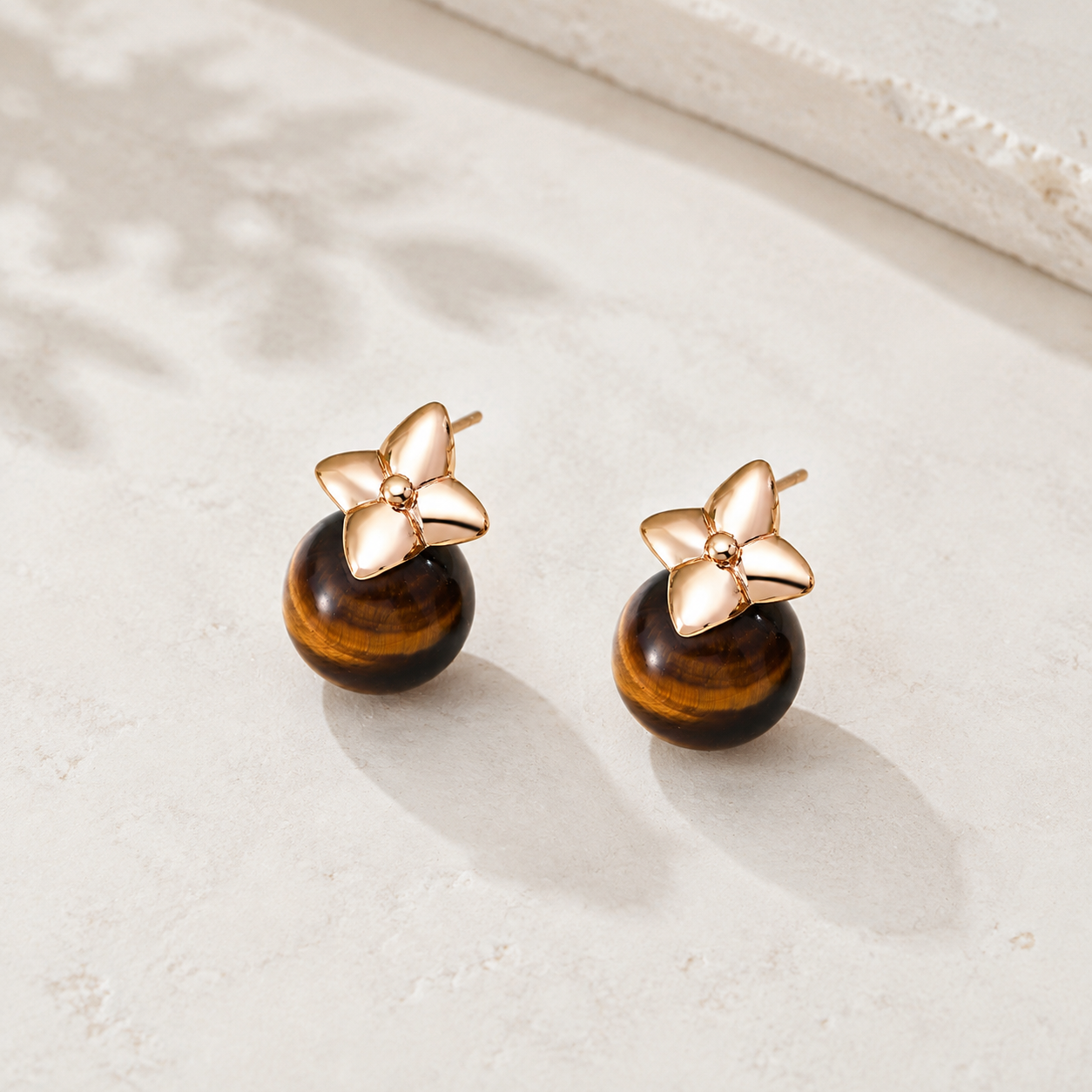 Vintage Gold four-leaf tiger eye stud earrings on an ivory display