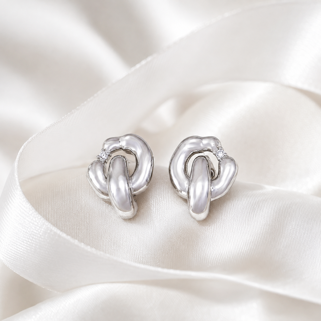 Pair of Silver Interlocking Zircon Earrings on ivory satin
