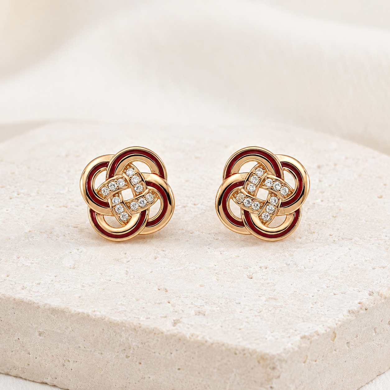 Vintage Gold enamel and cubic zirconia knot stud earrings on an ivory display