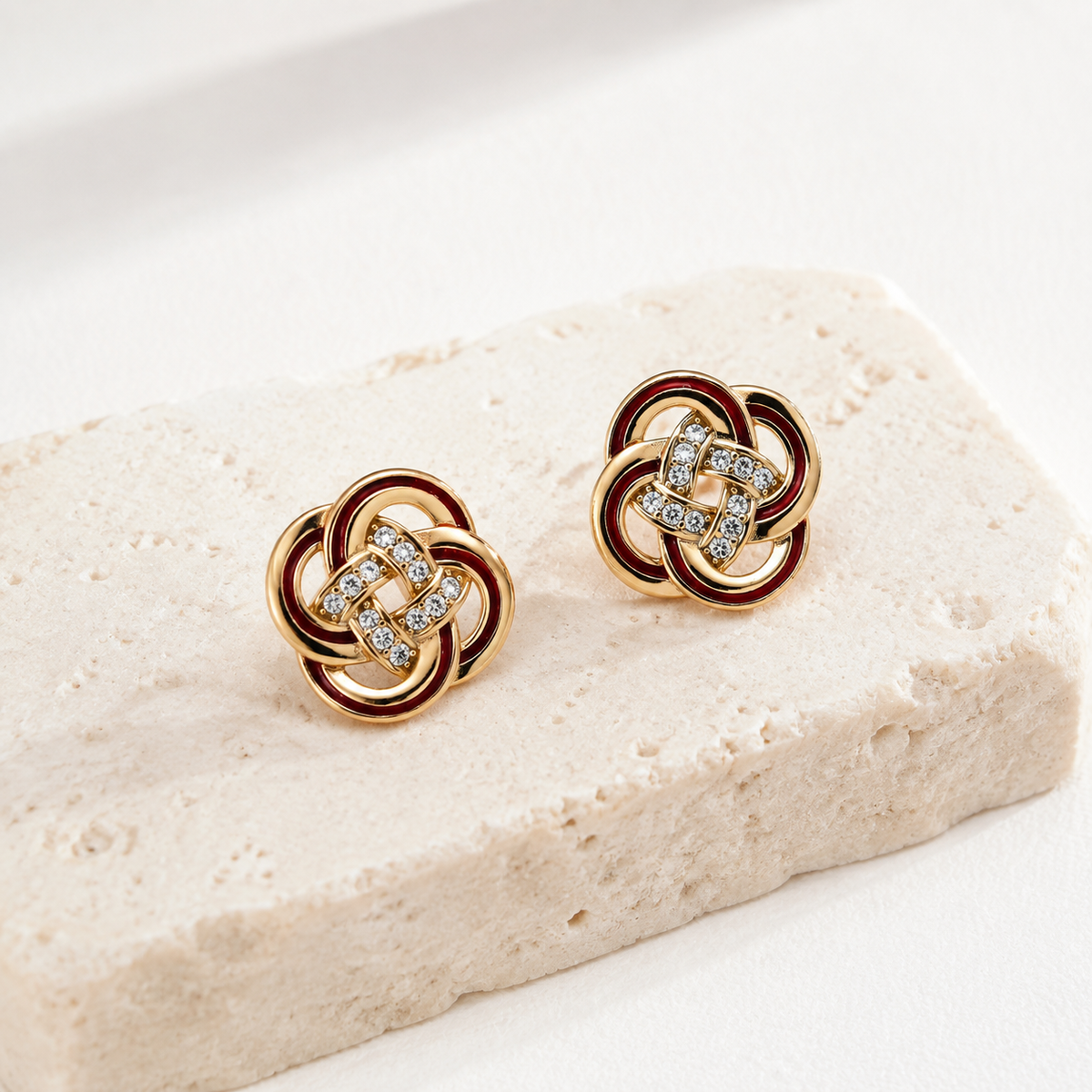 Vintage Gold enamel and cubic zirconia knot stud earrings on a stone display