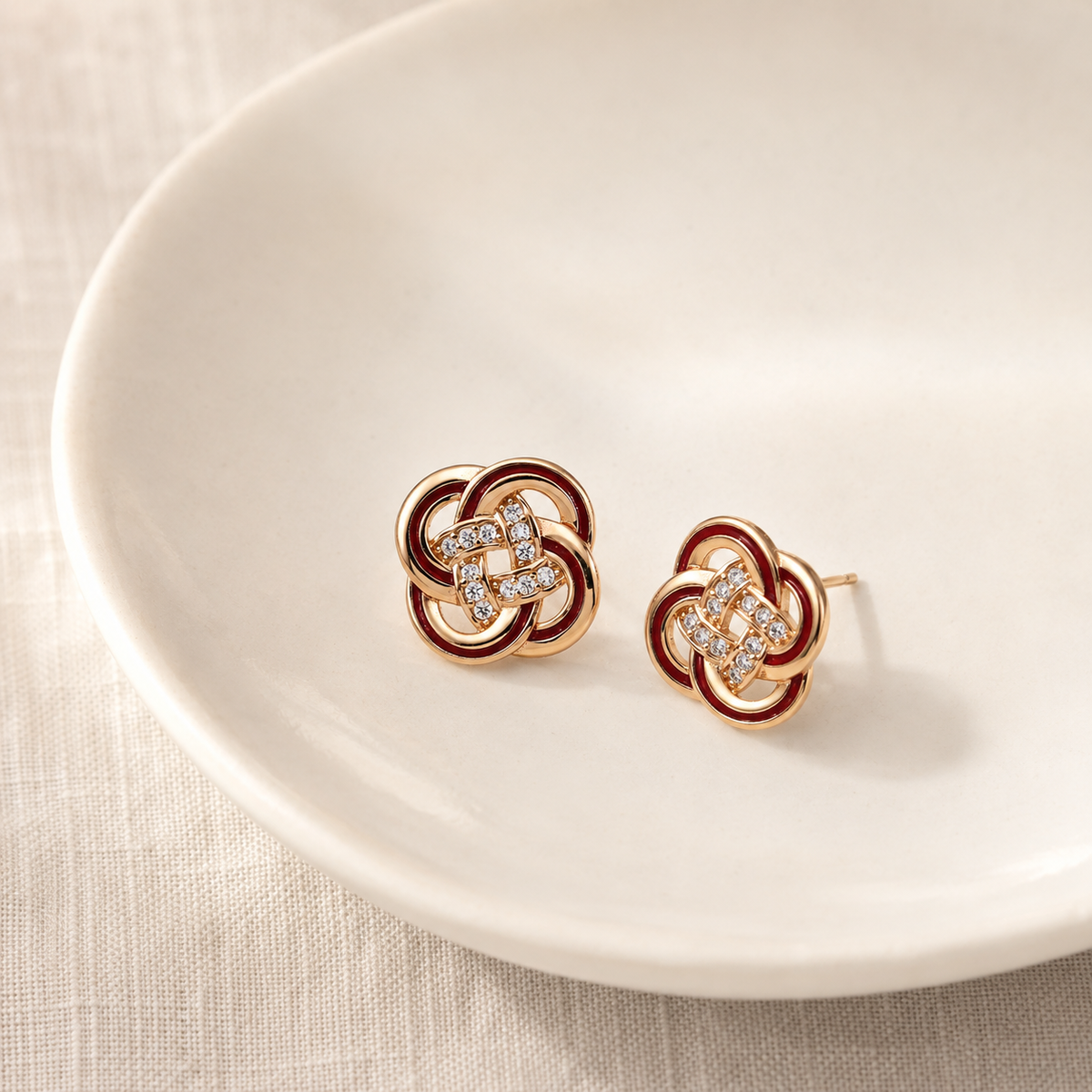 Vintage Gold enamel and cubic zirconia knot stud earrings on a ceramic dish
