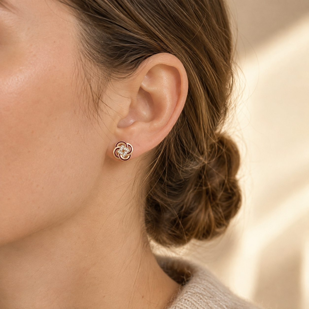 Close ear view of Vintage Gold enamel and cubic zirconia knot stud earrings