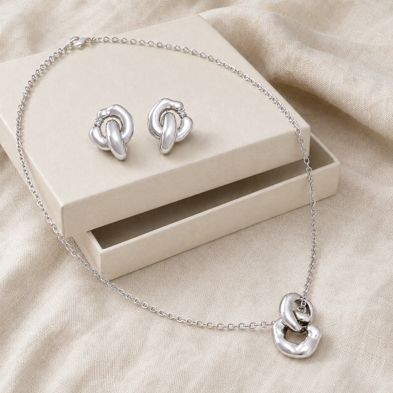 Silver Interlocking Jewelry Set arranged on an ivory jewelry box
