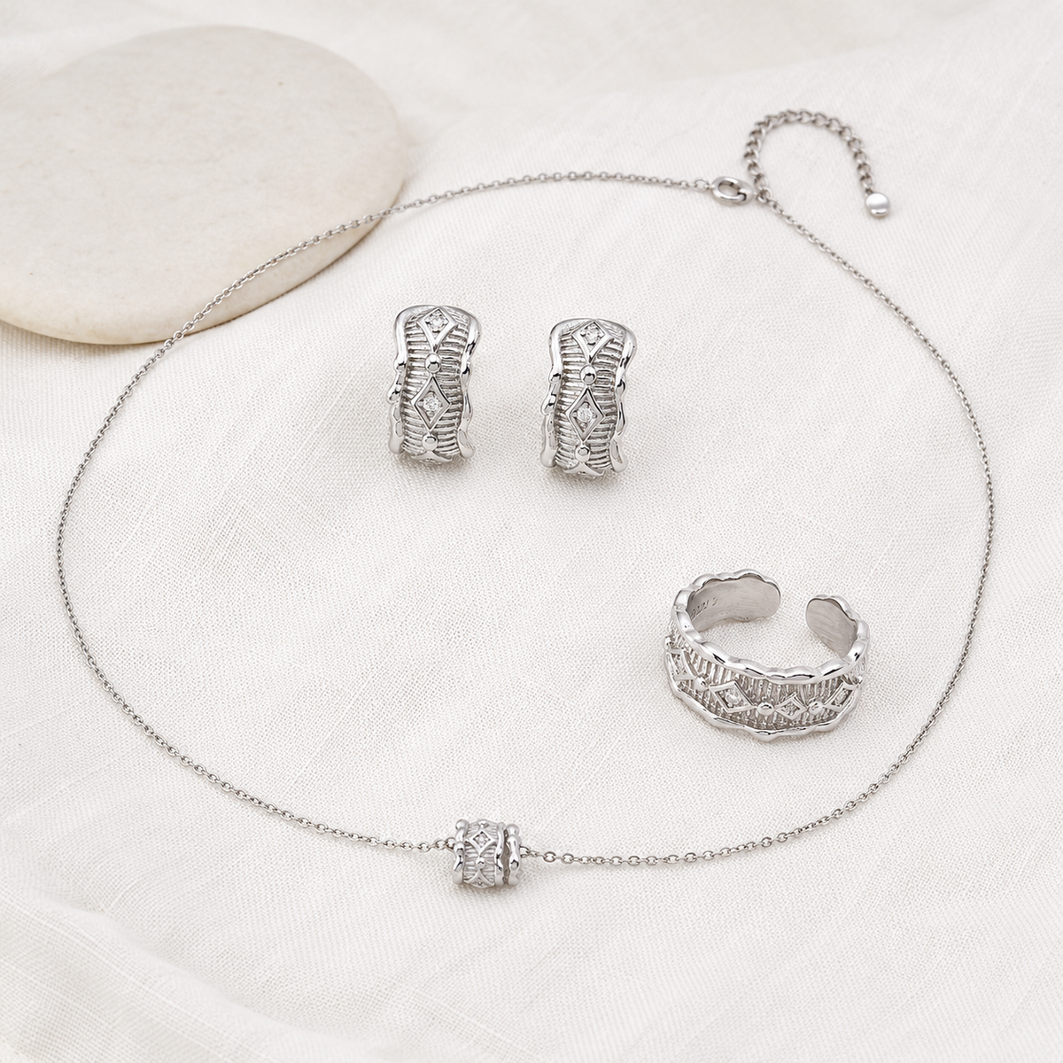 Silver zircon jewelry set arranged with ring, pendant necklace, and stud earrings