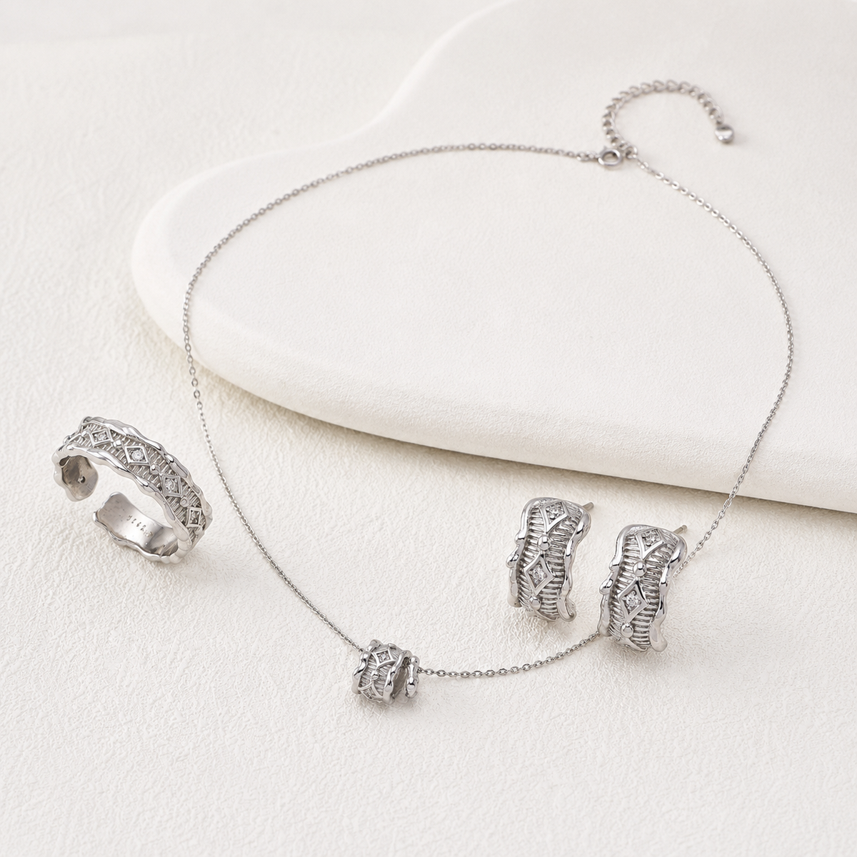 Silver zircon jewelry set with necklace, ring, and stud earrings on a soft display