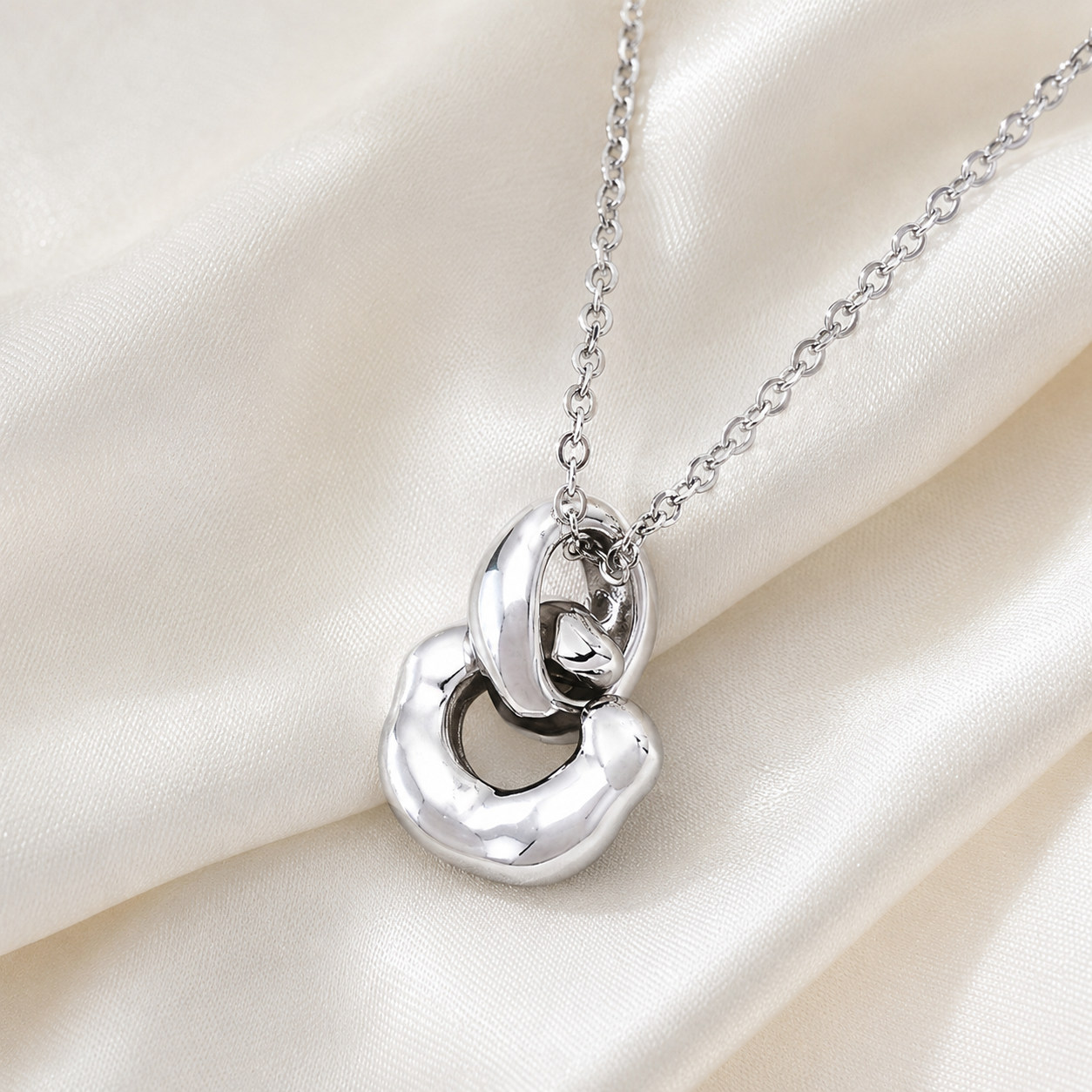 Close view of Silver Interlocking Pendant Necklace on ivory satin