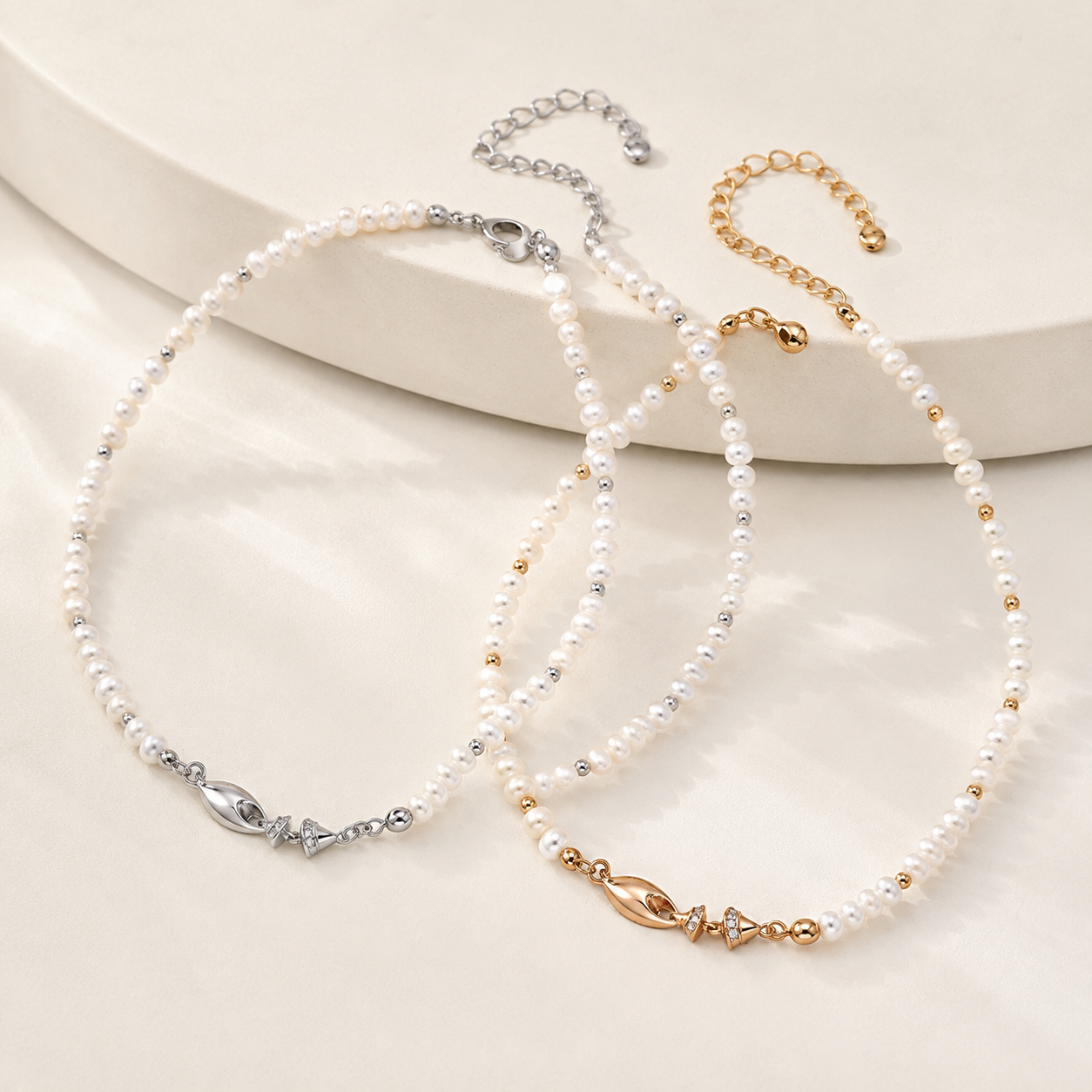 Vintage Gold and Silver natural pearl fish necklaces shown together on an ivory display