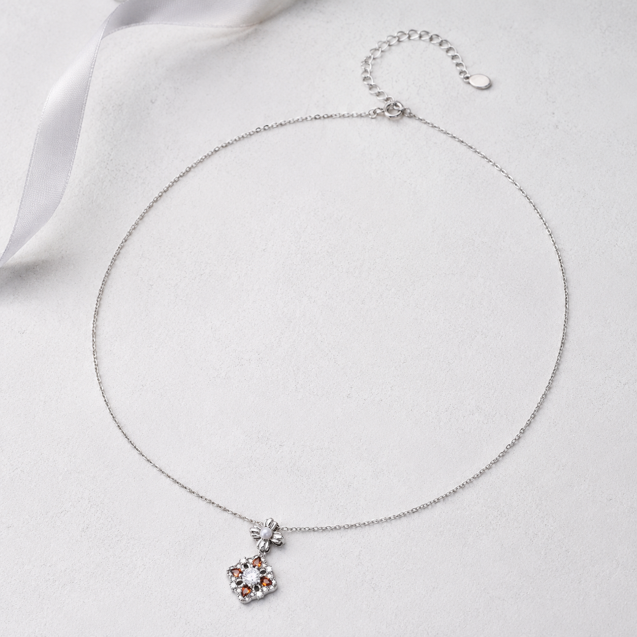 Silver auspicious bloom pearl pendant necklace on an ivory display