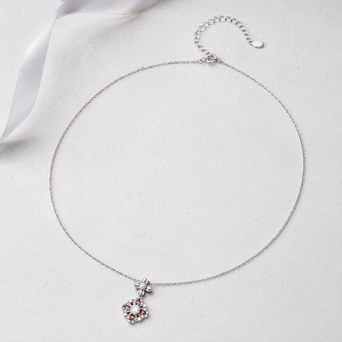Silver auspicious bloom pearl pendant necklace on an ivory display
