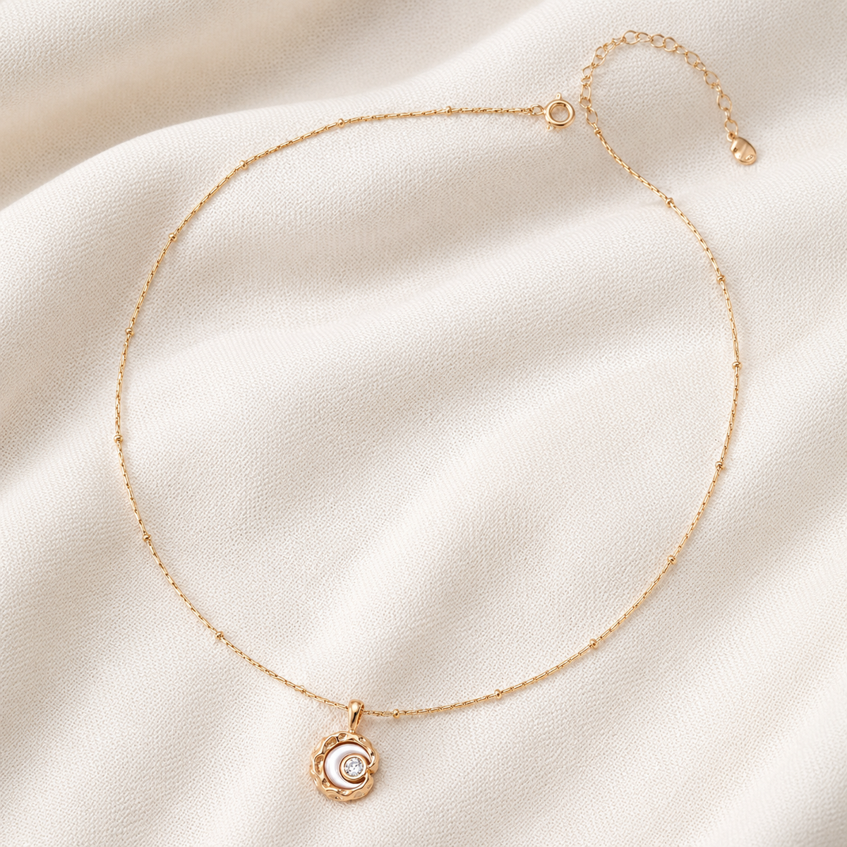 Full view of the Vintage Gold mother-of-pearl moon pendant necklace on textured fabric