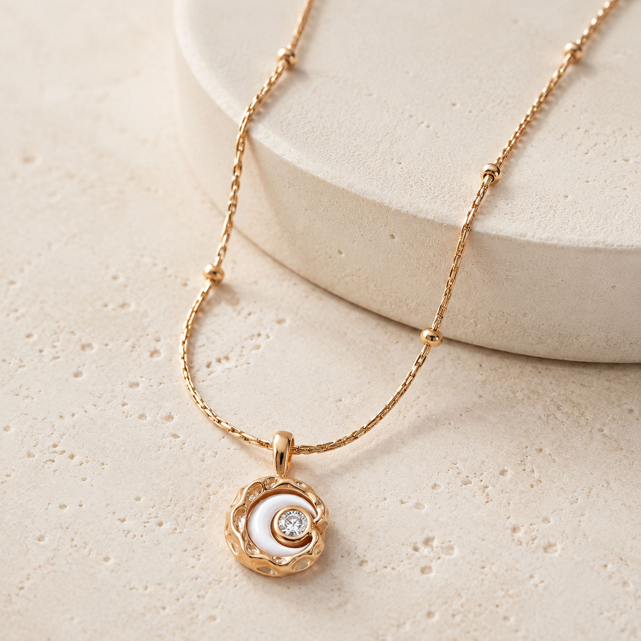 Vintage Gold mother-of-pearl and cubic zirconia moon pendant necklace on a stone display