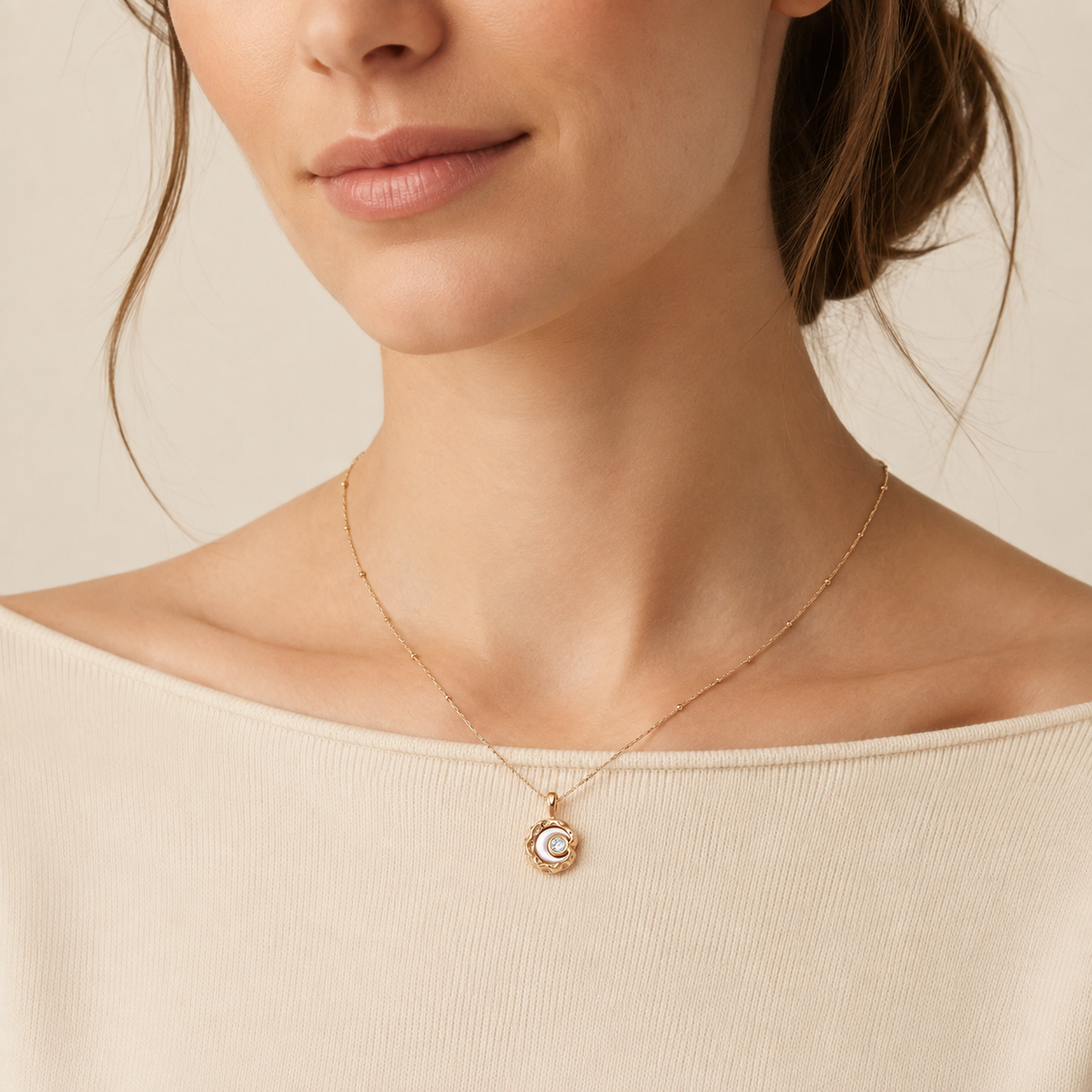 Close neckline view of the Vintage Gold mother-of-pearl moon pendant necklace with a cream top