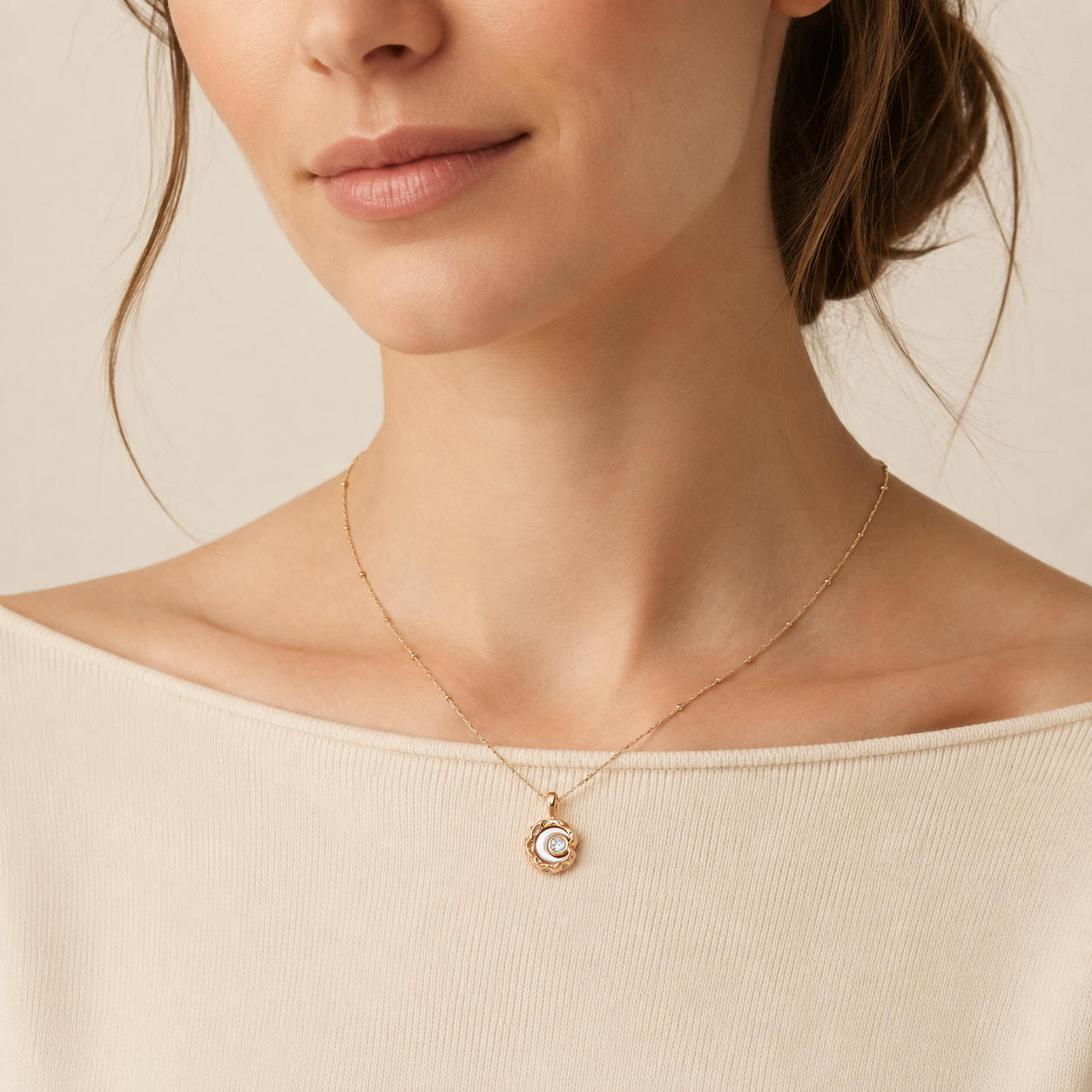 Close neckline view of the Vintage Gold mother-of-pearl moon pendant necklace with a cream top
