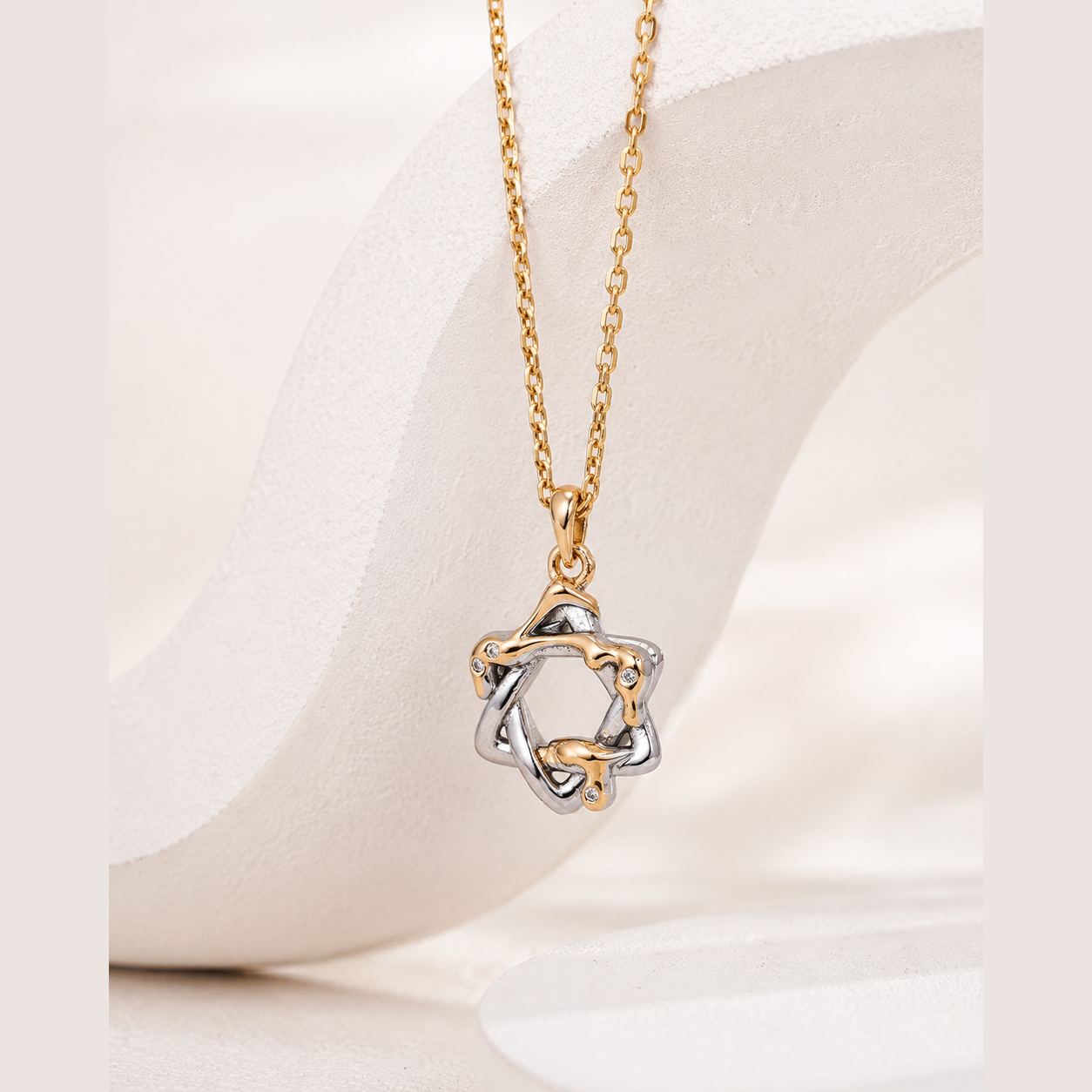 Mixed-tone Interwoven Star Pendant Necklace on a sculptural ivory display