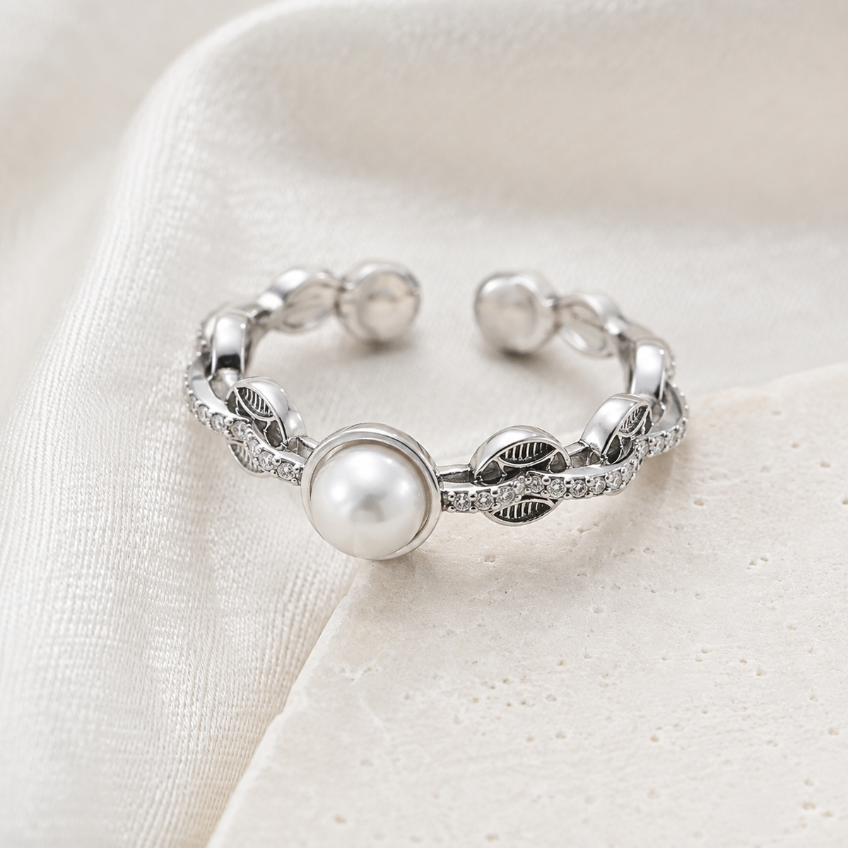 Silver pearl coin motif ring on textured fabric